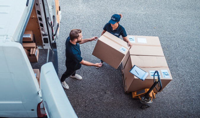 Two workers loading boxes into a van