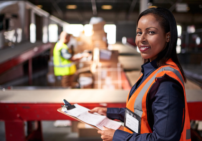 Woman standing with clipboard and safety vest